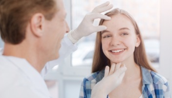 Young female getting face examined by male doctor
