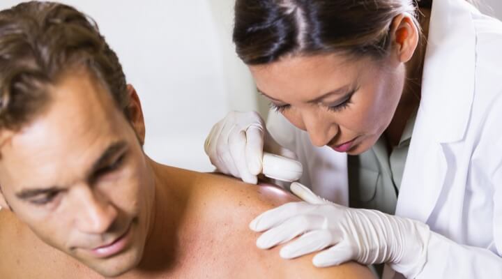 caucasian man getting skin exam by femal doctor